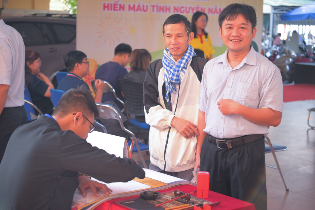 Ông đồ bày bút mực, giấy thơm để cho chữ phục vụ những người tham gia hiến máu - Ảnh: Ý NGUYỄN